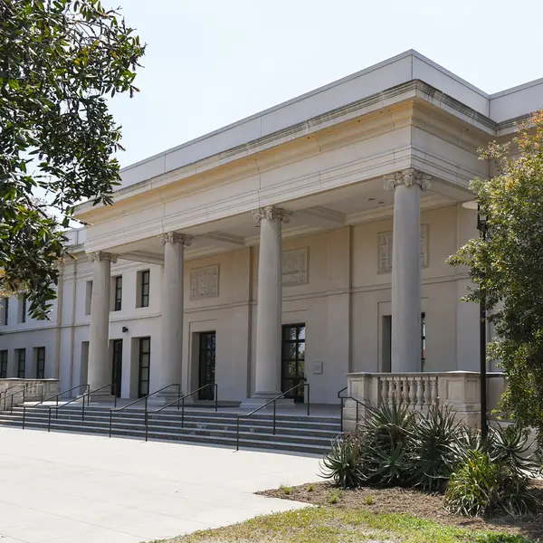 A large white building with columns and trees outside.