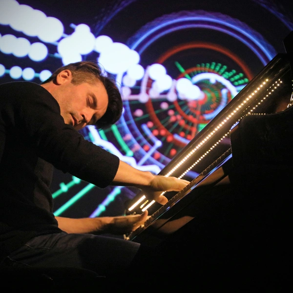 A musician sits at a lit piano.