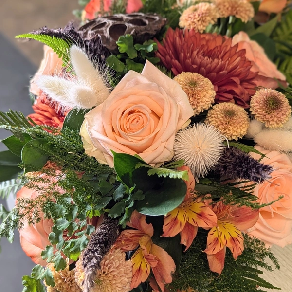 A bouquet of peach-colored roses, chrysanthemums, and other fresh flowers.