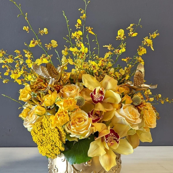 A flower arrangement of yellow and gold Cymbidium and Oncidium orchids.