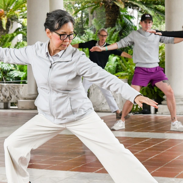 A person in a white athletic outfit and black glasses stands in an action pose.