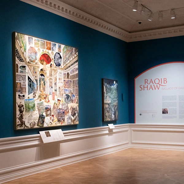 A gallery with large-scale artworks on blue walls.