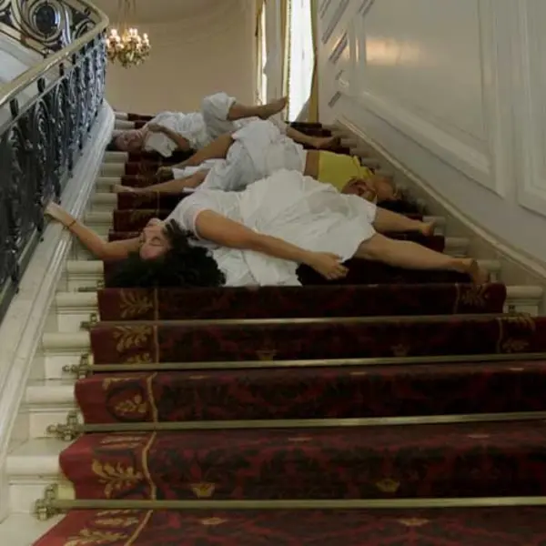 Video still depicting dancers on the staircase in the Huntington Art Gallery, from Apariciones/Apparitions