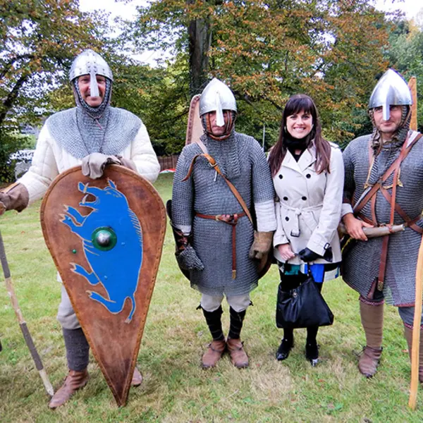 Medieval manuscripts curator Vanessa Wilkie in Battle, England, standing with visitors from France dressed as Norman soldiers