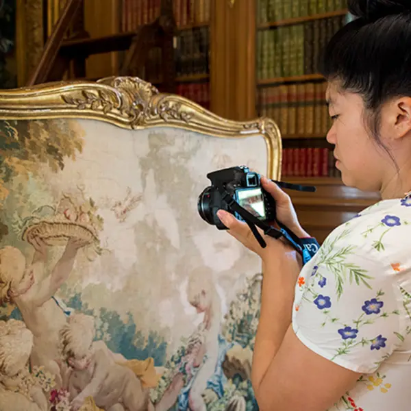 Artist Soyoung Shin photographs an 18th-century tapestry-covered fire screen in the Huntington Art Gallery