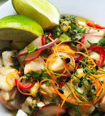 a plate of ceviche with lime wedges