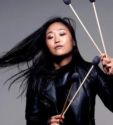 Asian American young woman musician dressed in black with drum sticks