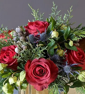 A fall flower arrangement highlighted by deep red roses.