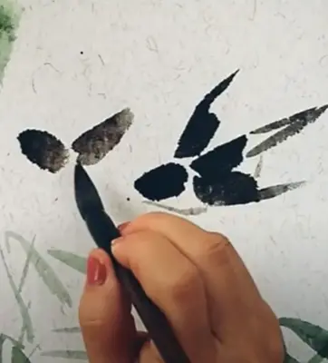 close up of a hand holding a brush doing Chinese brush painting