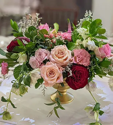 A pink and red rose center piece on a table.