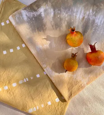 Dyed napkins are folded on a table, with small pomegranates on top.