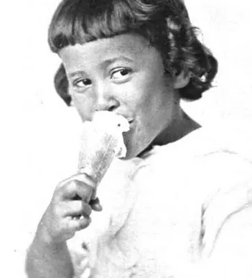 A vintage, grayscale photo of a young child eating ice cream.