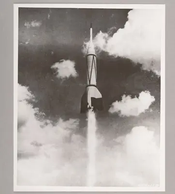 Black and white image of a rocket raising through clouds.