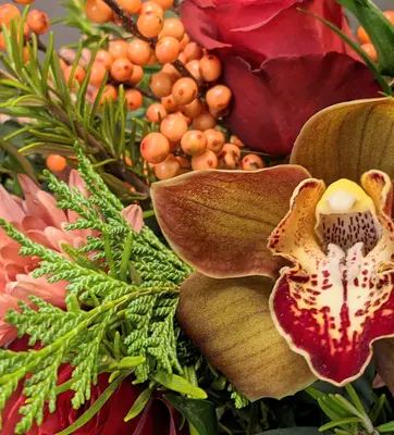 A flower arrangement in red and gold hues, with winter foliage.