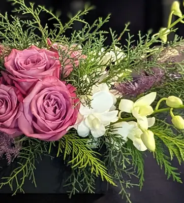 A flower arrangement in pink and white, with winter foliage.