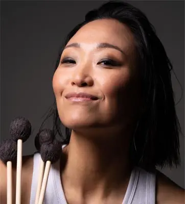 A person looks at the camera while holding mallets.