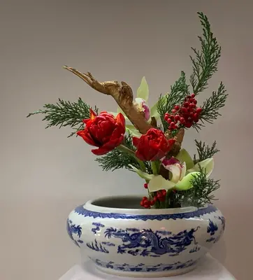 Chinese floral arrangement of red flowers in a blue-and-white vase.