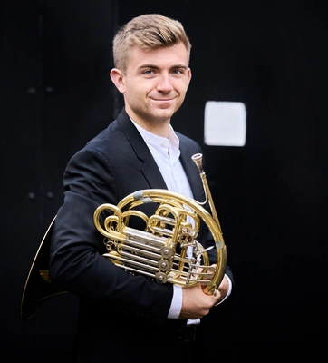 A musician holds a french horn.