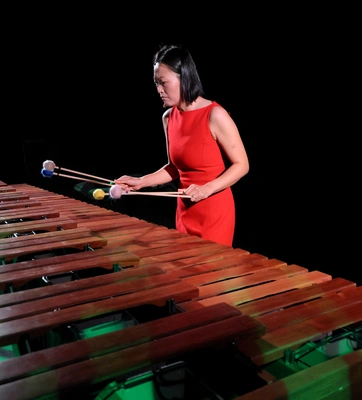 A musician plays xylophone while holding 4 mallets.