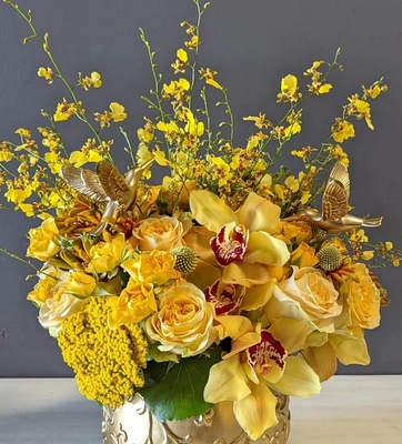 A flower arrangement of yellow and gold Cymbidium and Oncidium orchids.