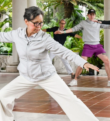 A person in a white athletic outfit and black glasses stands in an action pose.