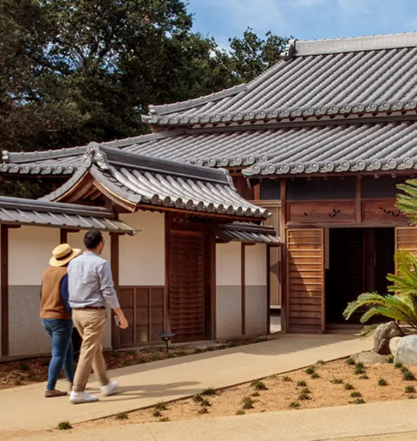 Two people walk toward the entrance to a traditional Japanese home.