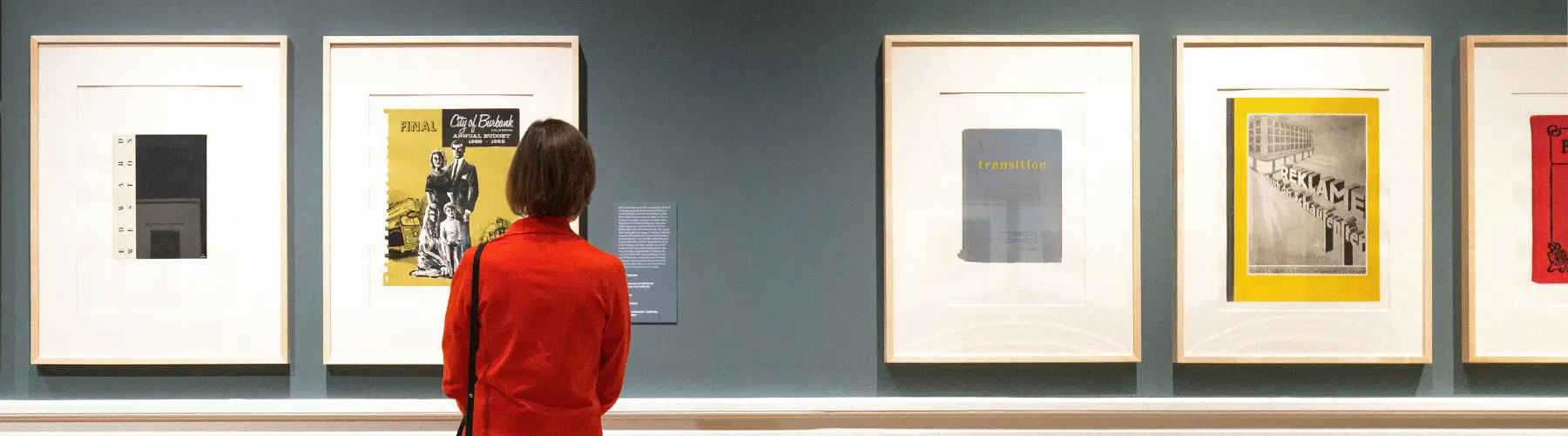 A person looks at framed artwork in a gallery.