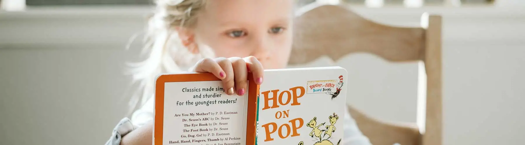Young girl is reading Dr. Seuss' "Hop on Pop"