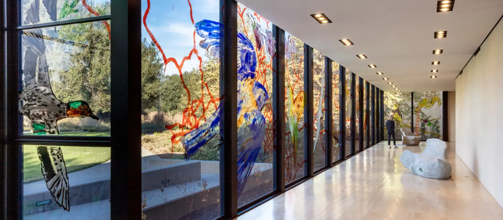 Looking down a glass-walled gallery space with bird painted on windows.