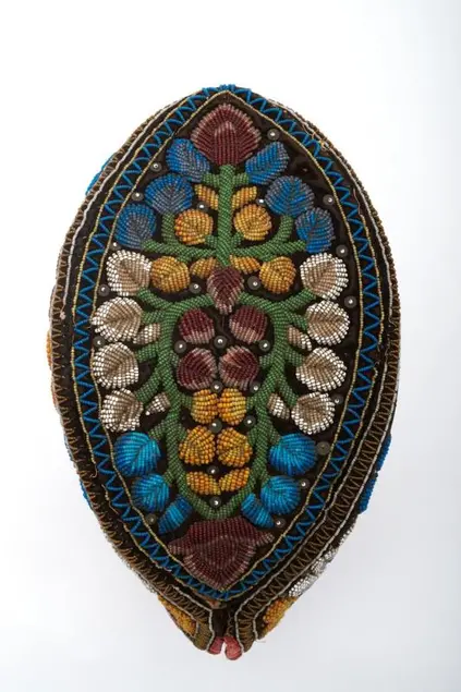 Black velvet cap in the shape of a pointed oval, with beadwork in blue, white, green, yellow, and red forming flowers and stems all over; made by a Haudenosaunee woman. 