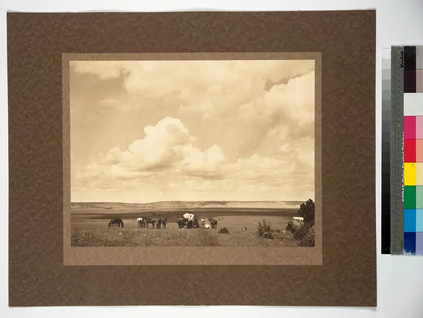 Sepia image of a desert scene with people and horses.