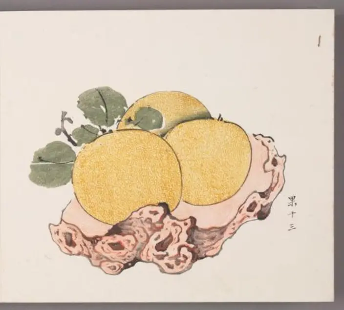Woodblock print featuring three citrons with leaves attached on an irregular wooden plate. 