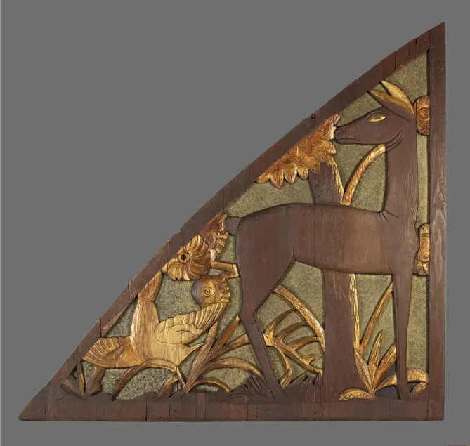Carved wood triangular panel. The panel includes a deer with gold eyes and ears and gold bird in flight. The background of the panel has gold and bare wood trees and grass and flowers.