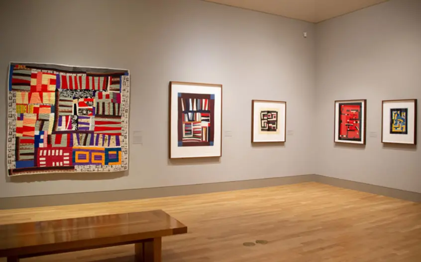 Bendolph’s President quilt hangs on gallery wall next to prints of other quilts.