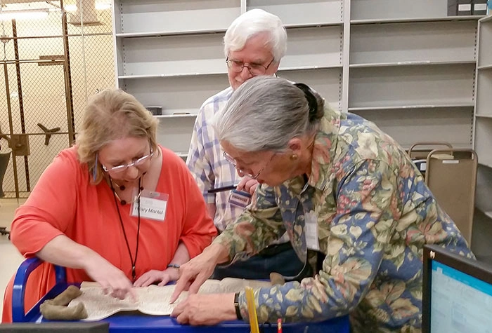 Hilary Mantel and Mary Robertson pore over a parchment legal document.