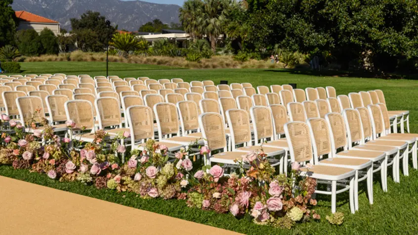 Beige and white wedding chairs with flower garlands in the foreground.