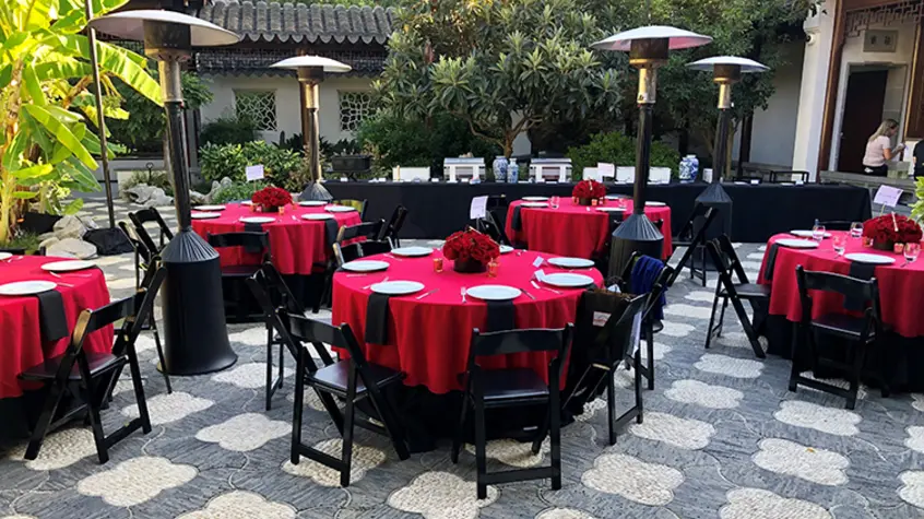 Richly-red tablecloth-ladden tables accented by black chairs.