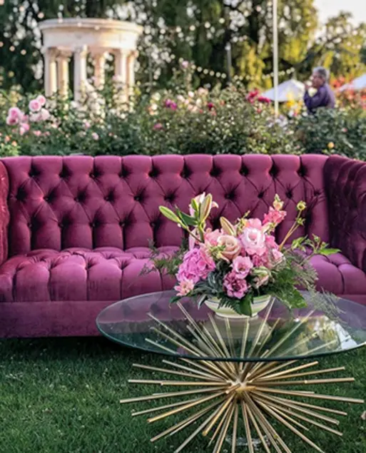 A tufted magenta couch sits behind a round coffee table with a golden sunburst base.