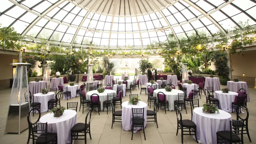 A wide angle shot of small round tables set up under a glass dome.