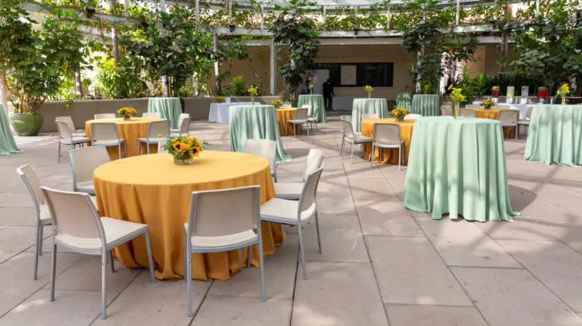 Peach and mint tablecloth-covered event tables are smartly placed in an outdoor courtyard.
