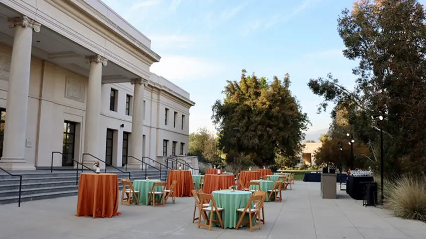 A courtyard filled with party tables covered in teal blue and darker peach tableclothes.