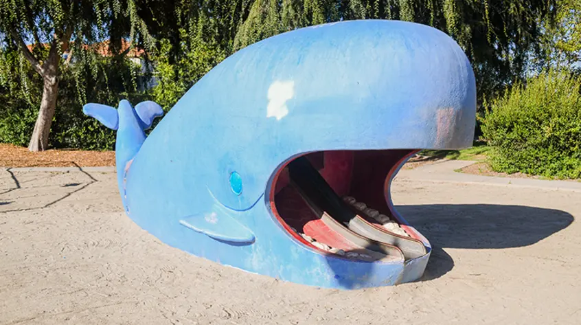A blue whale with a slide in its open mouth.