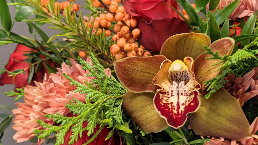 A flower arrangement in red and gold hues, with winter foliage.