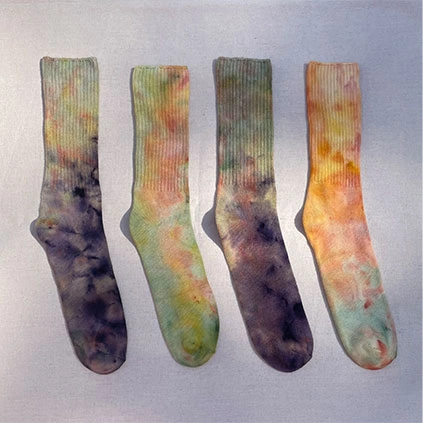 Four dyed socks aligned on a table.