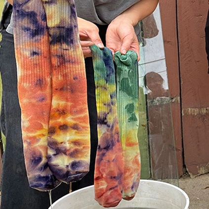 Freshly dyed socks hung over a bucket.