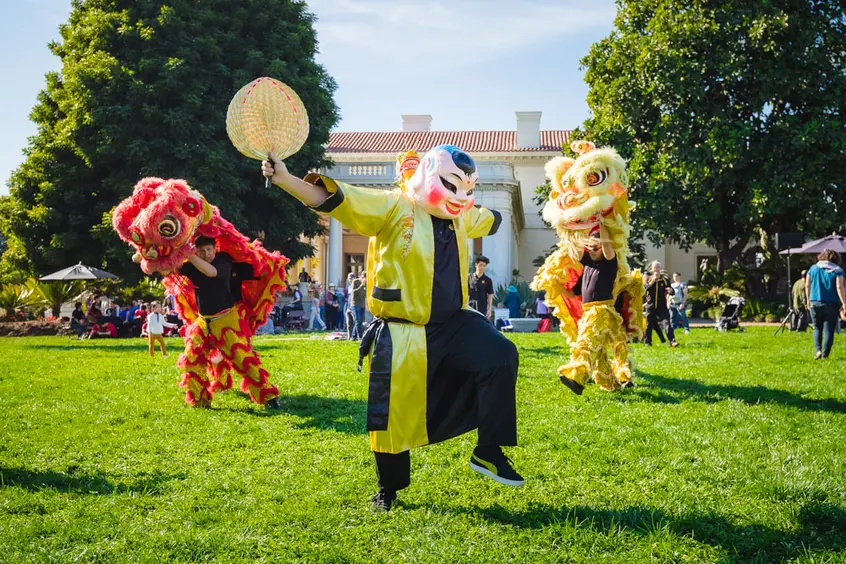 A masked dancer performs with two dragon puppets.