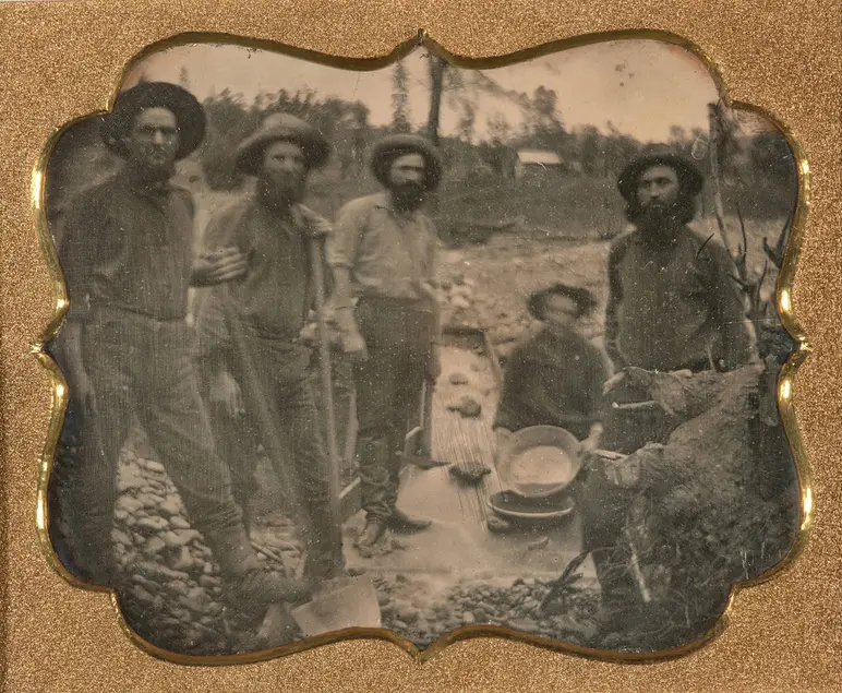 Five people with mining equipment pose for a photo.