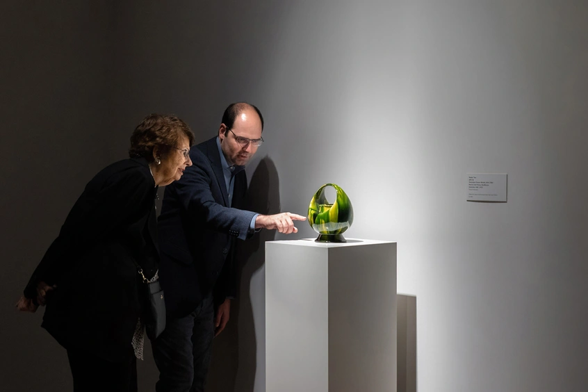 Two people stand looking at artwork in a gallery.