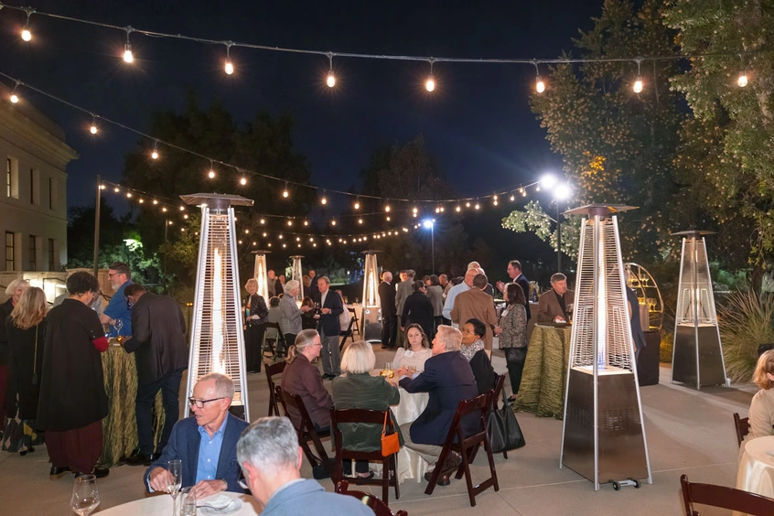 A large gathering of people in a decorated courtyard at nighttime.