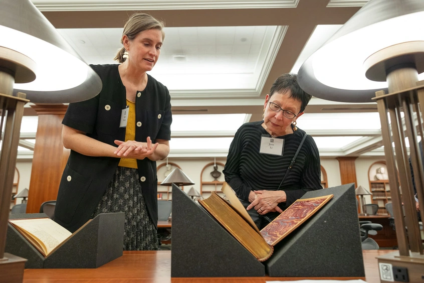 Two people look at an open book.